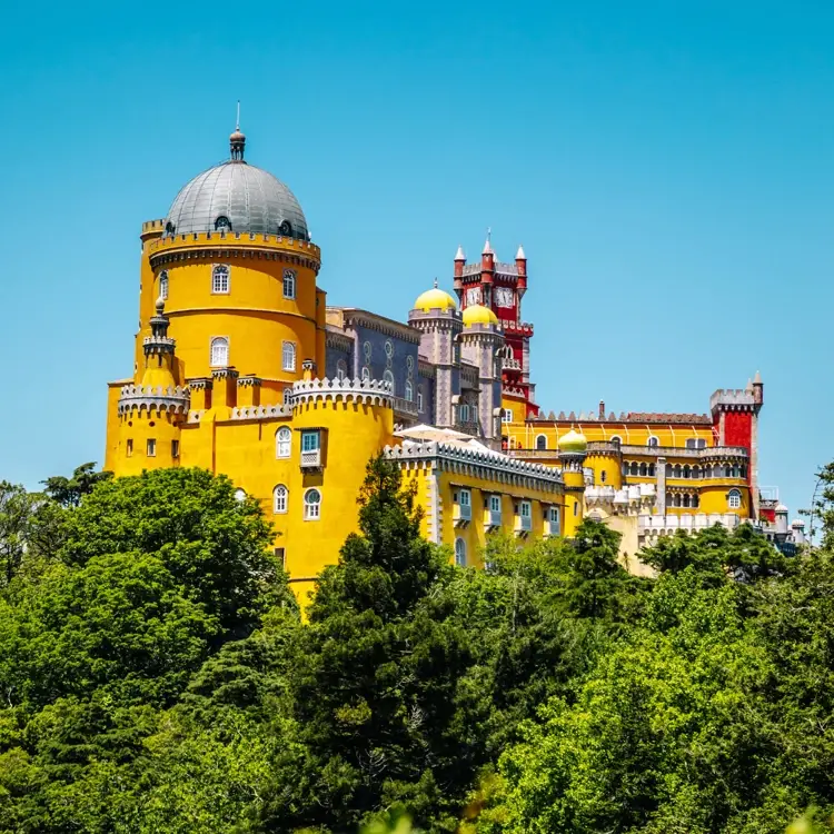 The yellow and red towers of Pena Palace above the treeline, Sintra